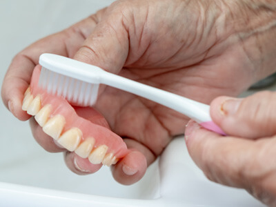 Close-up of dentures in Buda, TX being brushed