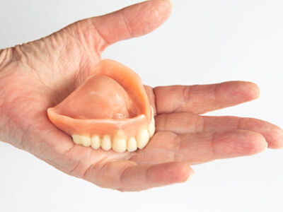 Close-up of hand holding dentures in Buda, TX