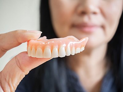 Close-up of woman holding a denture in Buda, TX