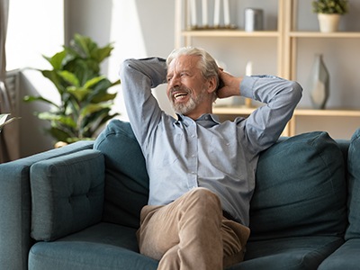 Senior bearded man sitting on a couch and smiling