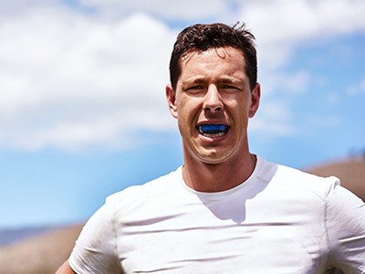 Man wearing blue mouthguard outside
